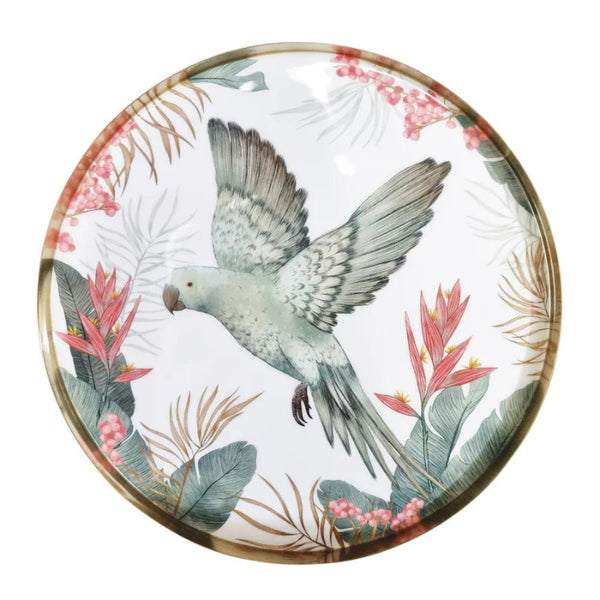 alt="A round serving tray with a tropical design featuring a flying bird amidst lush foliage"
