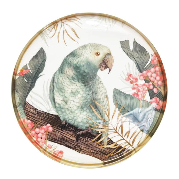 alt="A round serving tray with a tropical design featuring a bird resting on a tree branch"