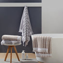 A stylish bathroom featuring a white tub, black wall, and bath linens, showcasing luxurious cotton comfort and design.