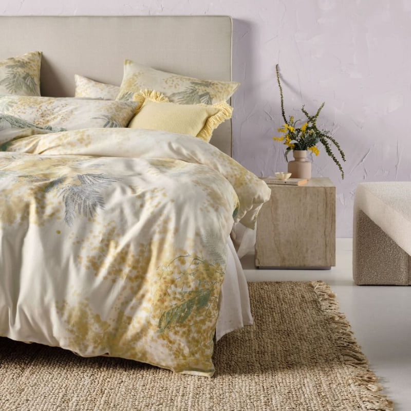 alt="A cotton quilt cover set outlined with a golden wattle pairs with European pillowcases in bedroom decor"