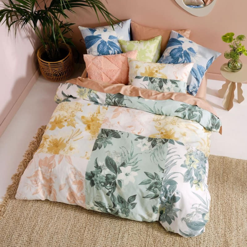 alt="Top view of a floral show-stopper quilt cover set paired with a European pillowcases and textured cushions in a luxurious bedroom"