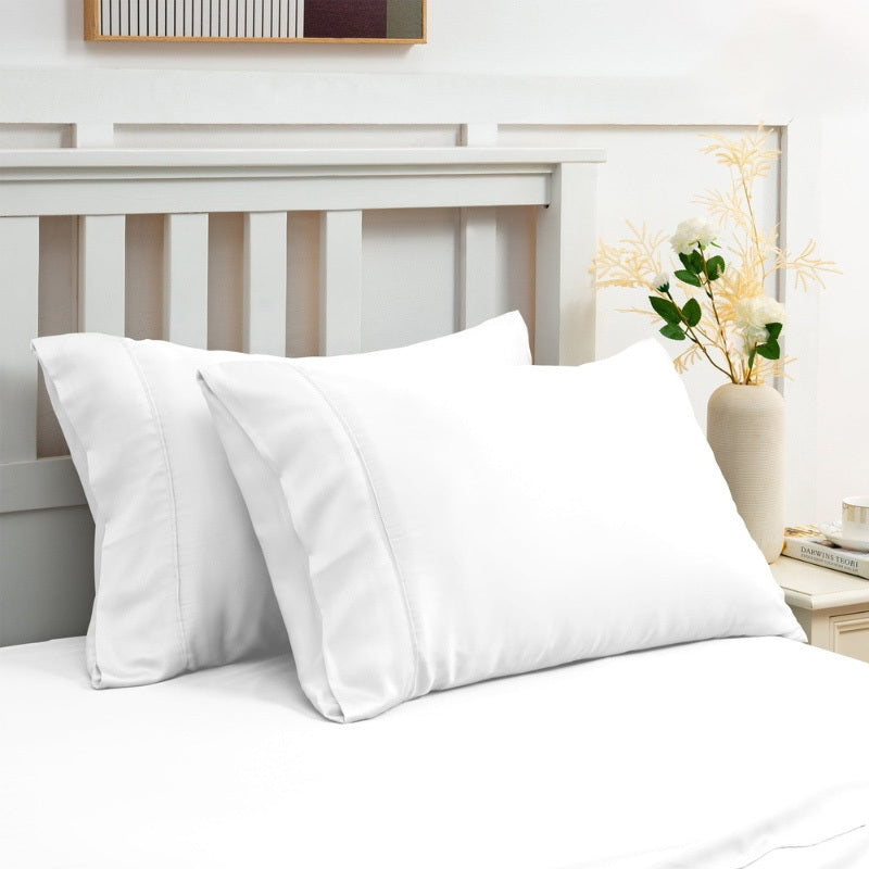 alt="White sheet set along with the pillows produce a lustrous silky smooth fabric to your bedroom"