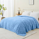 A cosy bed featuring a blue blanket, perfect for a stylish and inviting bedroom atmosphere.