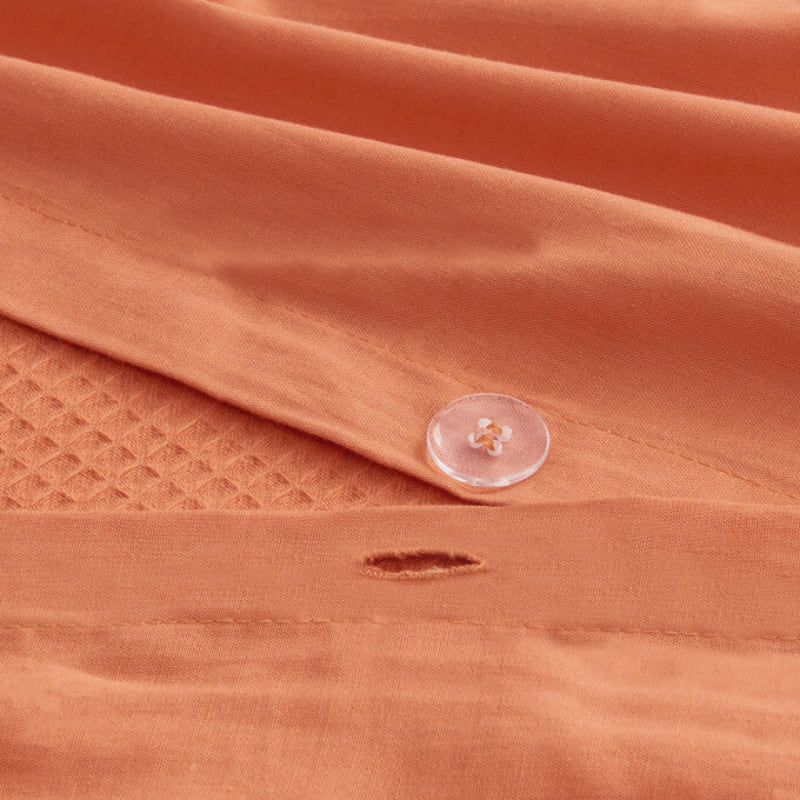 alt="Close-up details of an orange quilt cover set featuring a cotton waffle weave design"