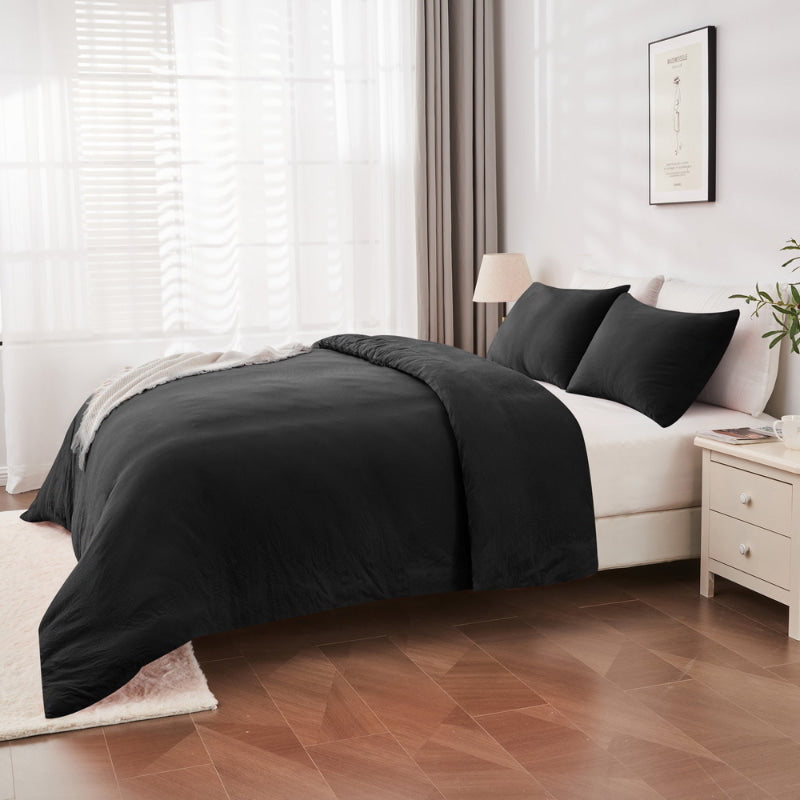 alt="Side view of a black Linenova quilt cover set neatly laid on a bed, showcasing its elegant and soft appearance."