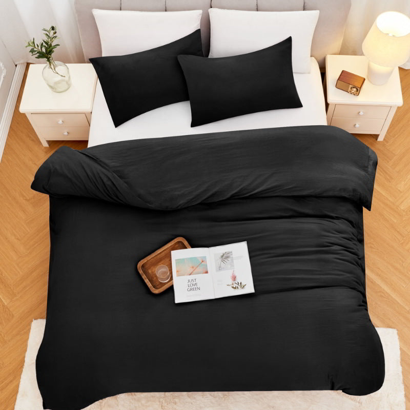 alt="Top view of a black Linenova quilt cover set neatly laid on a bed, showcasing its elegant and soft appearance."