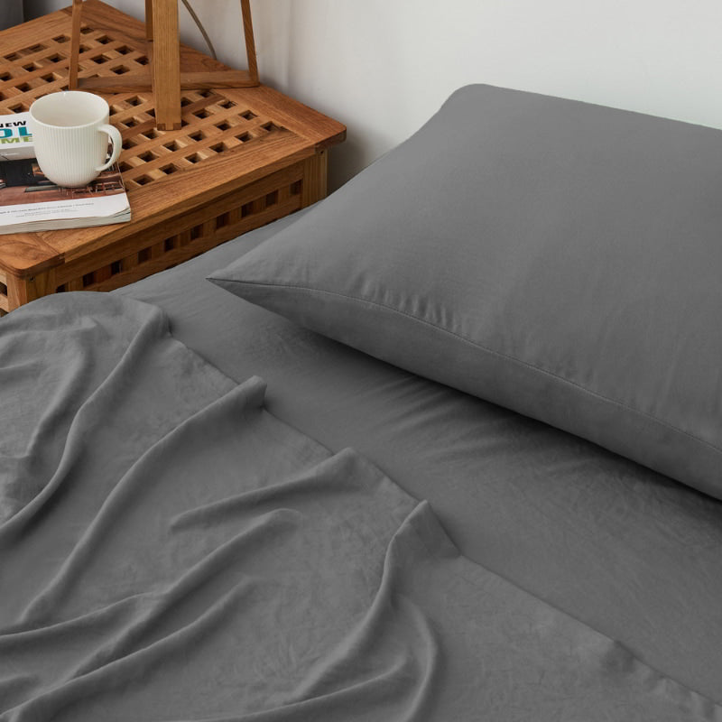 alt="A luxuriously soft charcoal cotton pre-washed sheet set in a cosy bedroom"