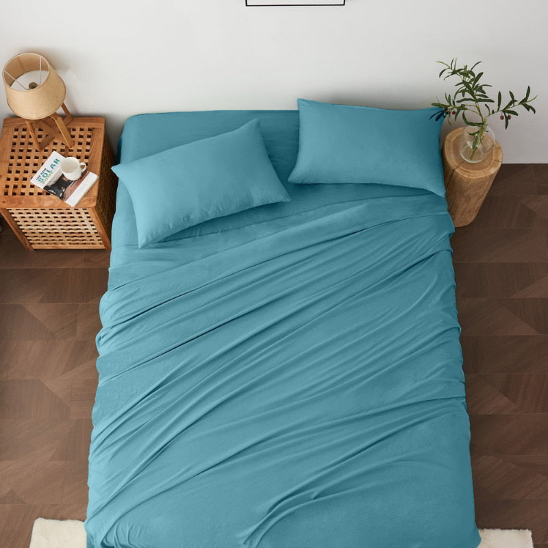 alt="A luxuriously soft slate blue cotton pre-washed sheet set in a cosy bedroom"