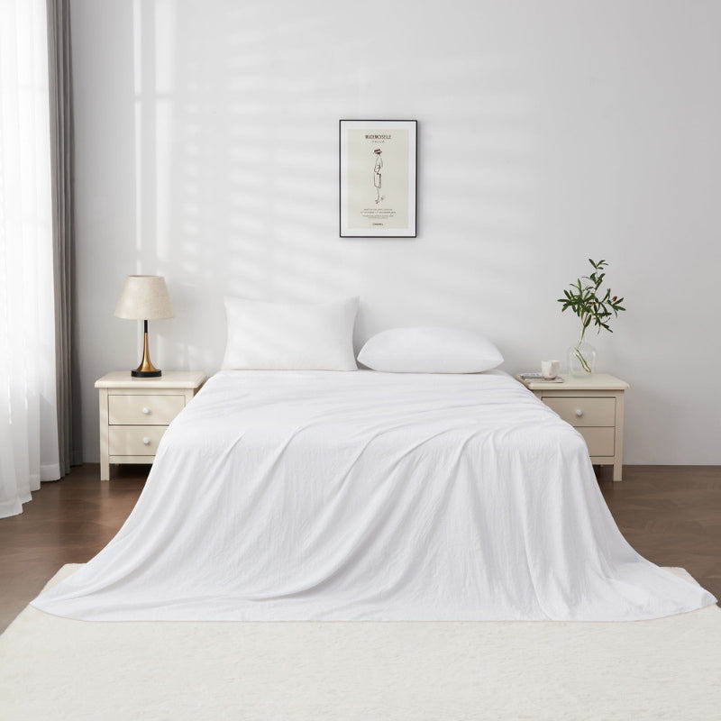 alt="A luxuriously soft white cotton pre-washed sheet set in a cosy bedroom"