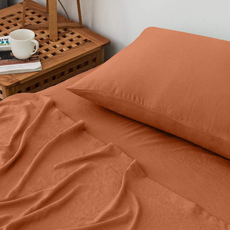 alt="A luxuriously soft rust cotton pre-washed sheet set in a cosy bedroom"