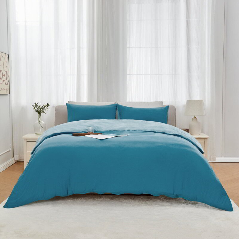 alt="Blue Linenova quilt cover set neatly laid on a bed, showcasing its elegant and soft appearance."