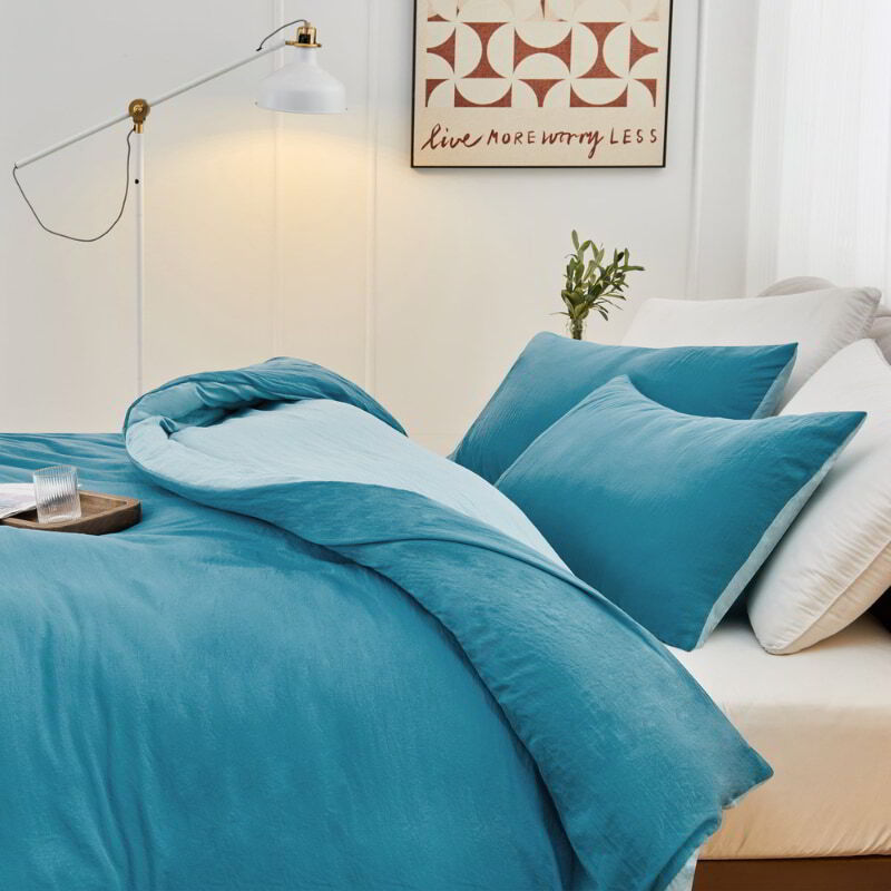 alt="Side view of a blue Linenova quilt cover set neatly laid on a bed, showcasing its elegant and soft appearance."