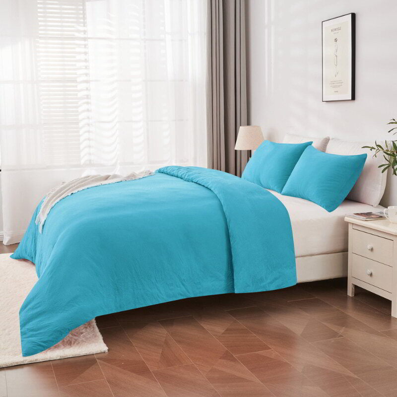 alt="Side view of a blue Linenova quilt cover set neatly laid on a bed, showcasing its elegant and soft appearance."