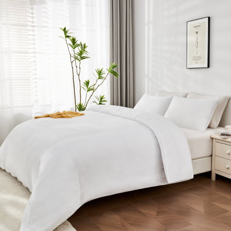 alt="Side view of a white Linenova quilt cover set neatly laid on a bed, showcasing its elegant and soft appearance."