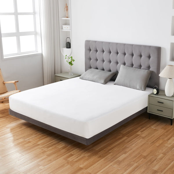 alt="A white fitted mattress protector, 100% waterproof and designed with a top-notch TPU layer, adds sophistication to the bedroom's appearance"