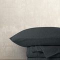 alt="A midnight-coloured bamboo cotton sheet set featuring its minimal, inviting softness and comfort"