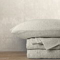 alt="An oatmeal-coloured bamboo cotton sheet set,featuring its minimal, inviting softness and comfort"