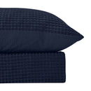 Close-up of navy waffle texture and quilt cover detailing on a modern bed

