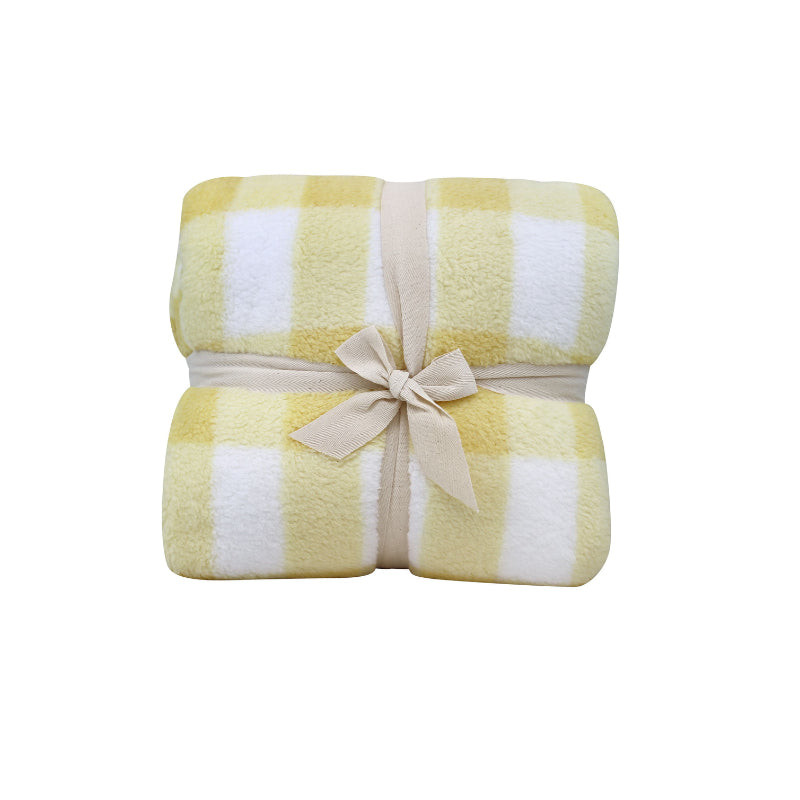 Front packaging details of a cosy bed with a yellow and white blanket featuring a large checkered pattern creates a bold visual grid, adding colour and pattern to the room's decor.