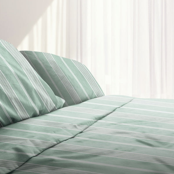 Bed with green and white striped sheet set, showcasing uniform horizontal stripes for a minimalist or nautical-themed bedroom decor.