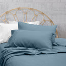 A clean and classic blue bed with matching sheets and pillows on a cosy bedroom, made of 100% microfibre for a soft and warm feel.