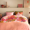 Detail view of pillow and floral pattern with soft brown sheets and bedside lamp