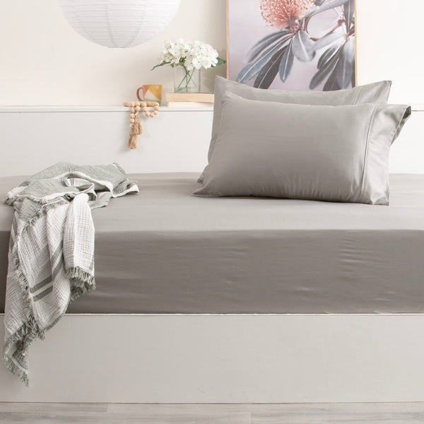 alt="A luxurious bed with charcoal fitted sheets and pillows, made from a bamboo-cotton blend for a naturally breathable and silky smooth experience."