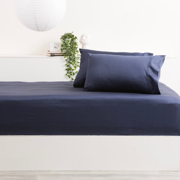 alt="Experience the softness of a bamboo cotton blend bed set with a shade of indigo sheet and pillow, offering a silky smooth feel."