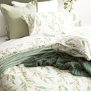 Flannelette bedding with native Australian leaf print layered with a green throw and white sheets
