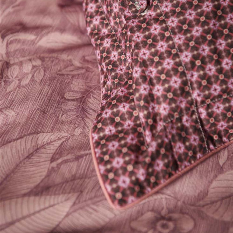 alt="Close up look of an elegant Casa dei Fiori quilt cover with intricate floral designs, and a reversible print of tiny flowers with the presence of pillow."
