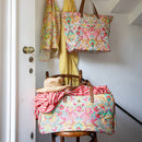 alt="Featuring a stylish yellow travel bag with ample storage space and intricate floral design in a chair."