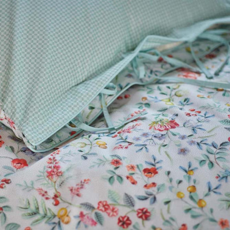 alt="Closer look of a quilt cover with delicate all-over floral print and reversible stylized tile pattern."