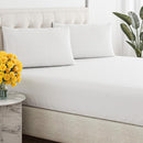 Close-up of a smooth, white, breathable cotton sheet draped over a tufted bed base