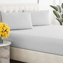 Close-up of a smooth, light grey, breathable cotton sheet draped over a tufted bed base