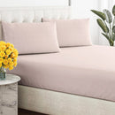 Close-up of a smooth, pink, breathable cotton sheet draped over a tufted bed base