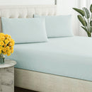 Close-up of a smooth, sage, breathable cotton sheet draped over a tufted bed base