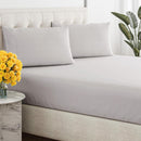 Close-up of a smooth, grey, breathable cotton sheet draped over a tufted bed base