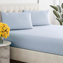 Close-up of a smooth, light blue, breathable cotton sheet draped over a tufted bed base