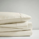 A stack of ivory sheet set, showcasing the luxurious 700 Thread Count Renee Taylor Sheet Set.