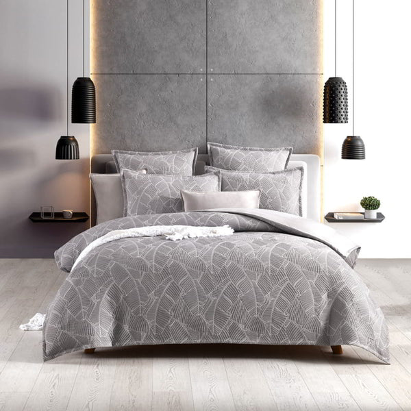 alt="A modern bedroom with grey and white quilt cover set, neutral-toned with a tropical banana leaf design, perfect for a boho look."
