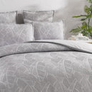 alt="Close-up look of a grey and white quilt cover, neutral-toned with a tropical banana leaf design, perfect for a boho look."