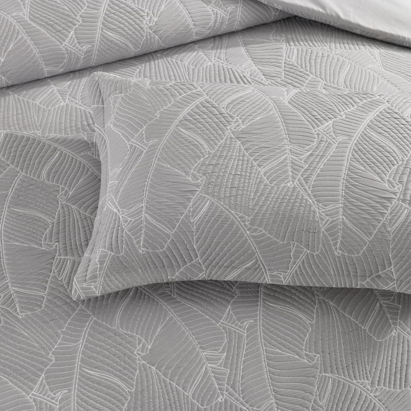 alt="A grey and white pillowcase, neutral-toned with a tropical banana leaf design, perfect for a boho look."