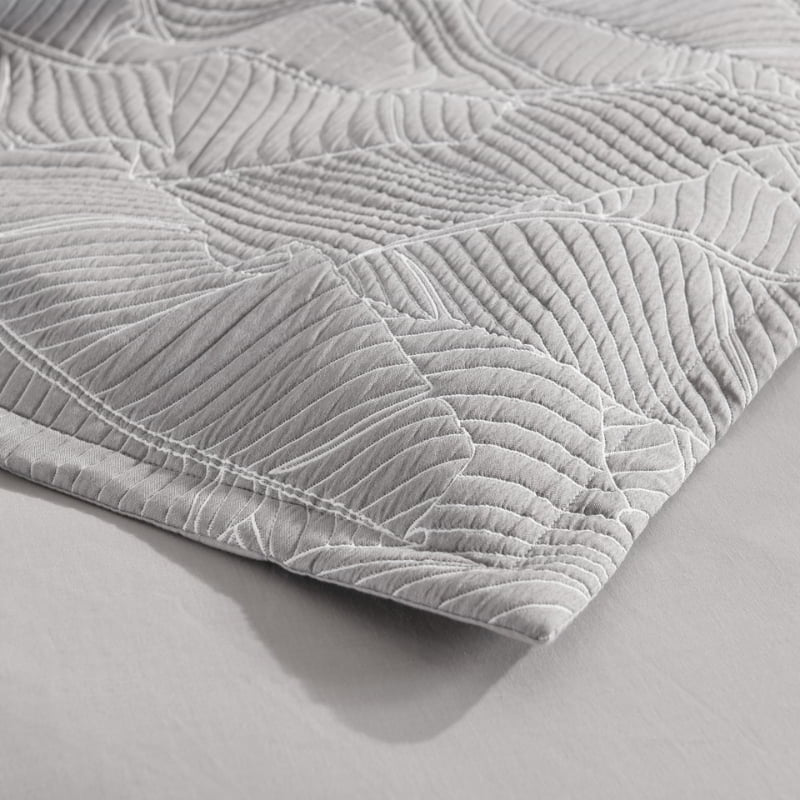 alt="Zoom in details of a grey and white quilt cover, neutral-toned with a tropical banana leaf design, perfect for a boho look."