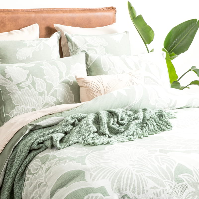 Elegant bed adorned with sage green floral patterned quilt cover set.