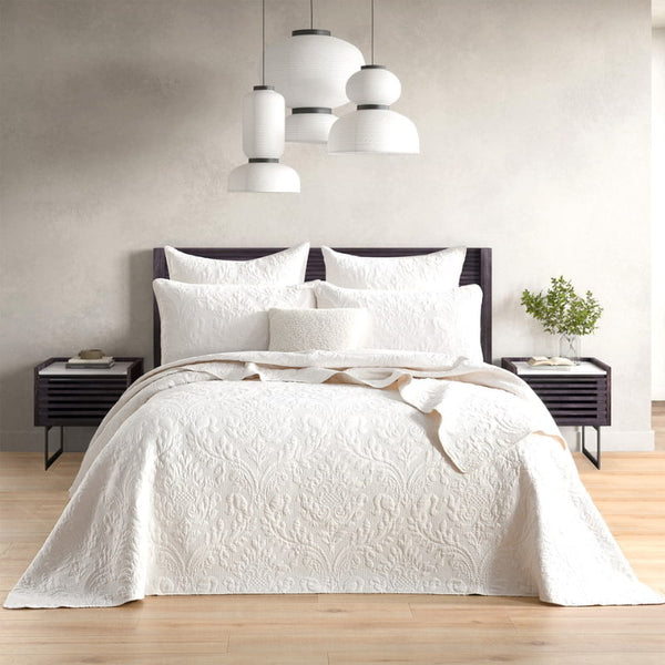 alt="A luxurious coverlet featuring a damask woven style fabric and intricate textile in a cosy bedroom."