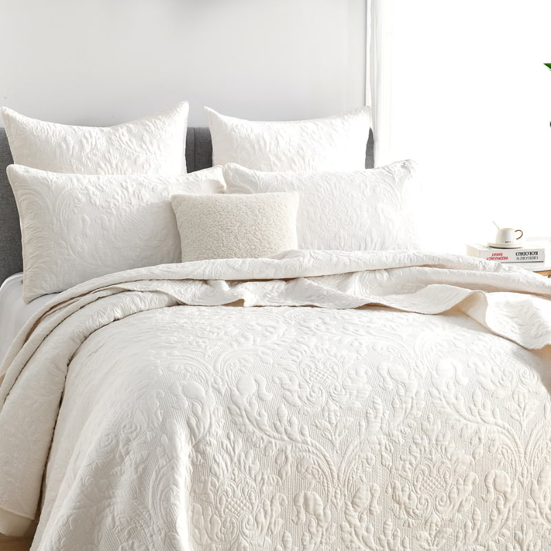 alt="A luxurious coverlet and european pillowcase featuring a damask woven style fabric and intricate textile in a cosy bedroom."