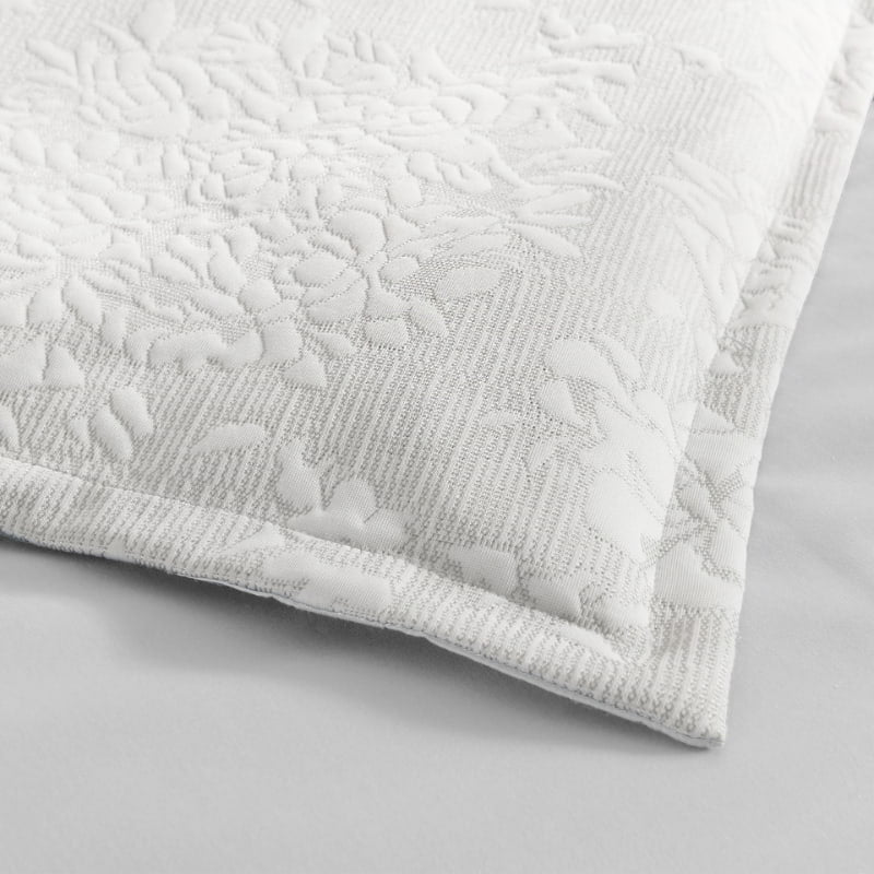 alt="Close up details of an ivory european pillowcase infused with blooming flower bundles"