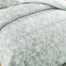 Detailed view of the quilted cotton texture and leaf motif on bed
