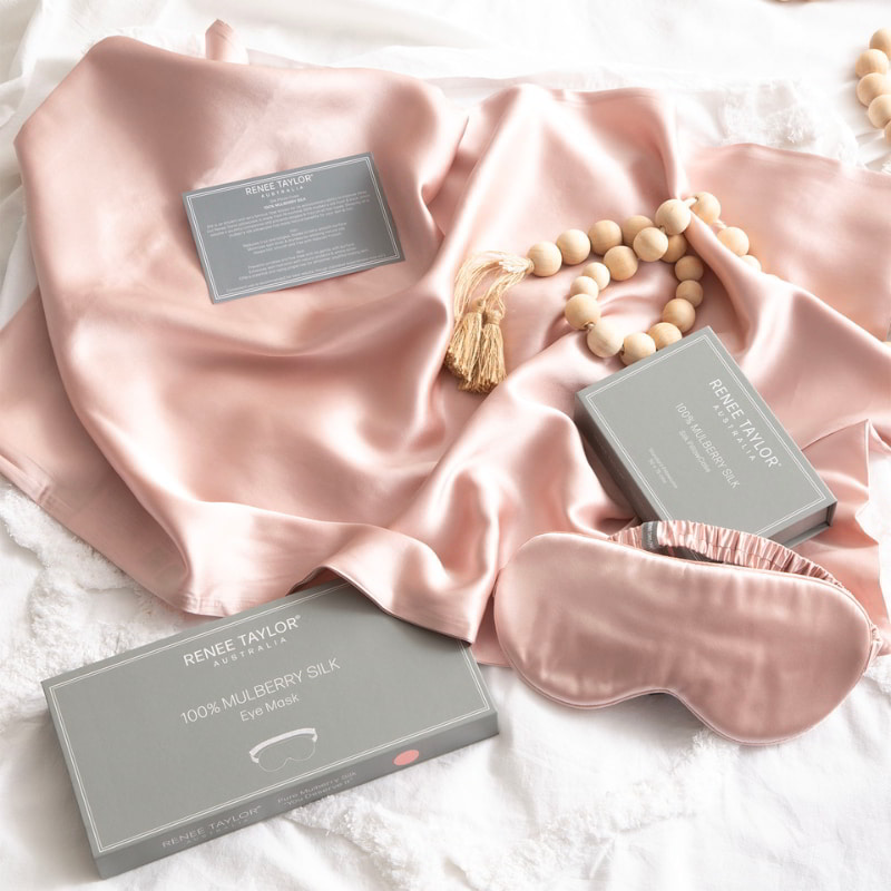 alt="A pink satin standard pillowcase, and eye mask made from 100% pure mulberry silk."