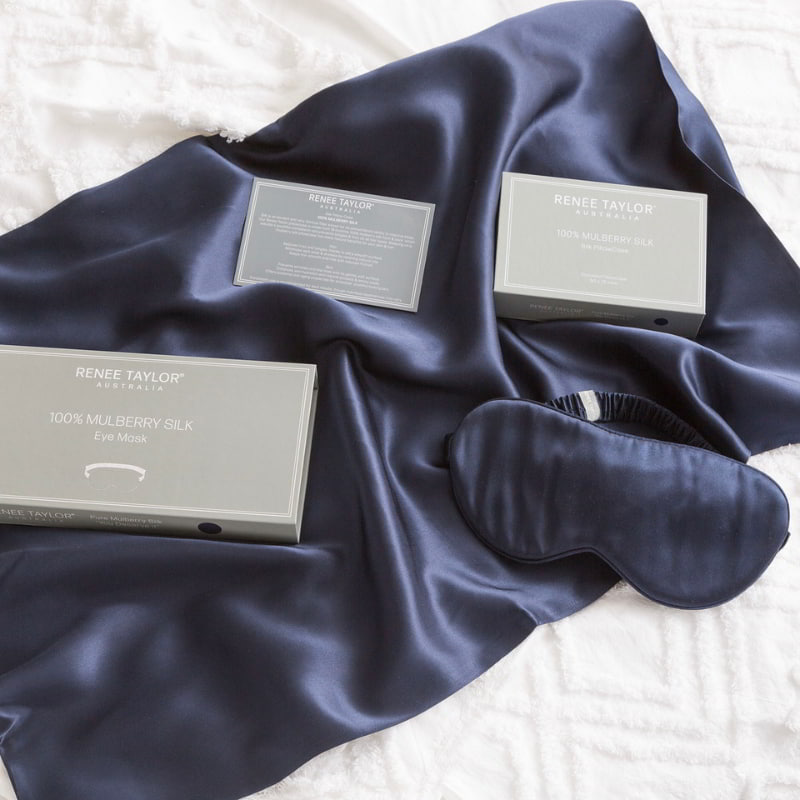 alt="A luxurious navy satin eye mask with packaging box made from 100% pure mulberry silk. Wake up feeling refreshed and rejuvenated with this gentle and hydrating mask."